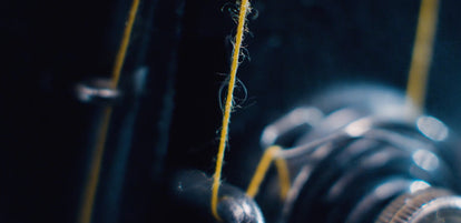 Extremely blurred close-up shot of thread weaved through a sewing machine spindle.