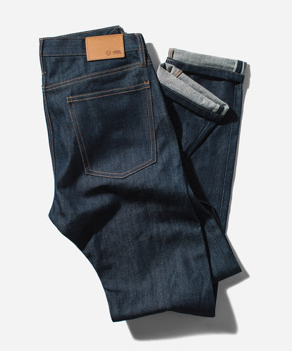 Flat lay of a pair of loosely-folded denim jeans on a white background.