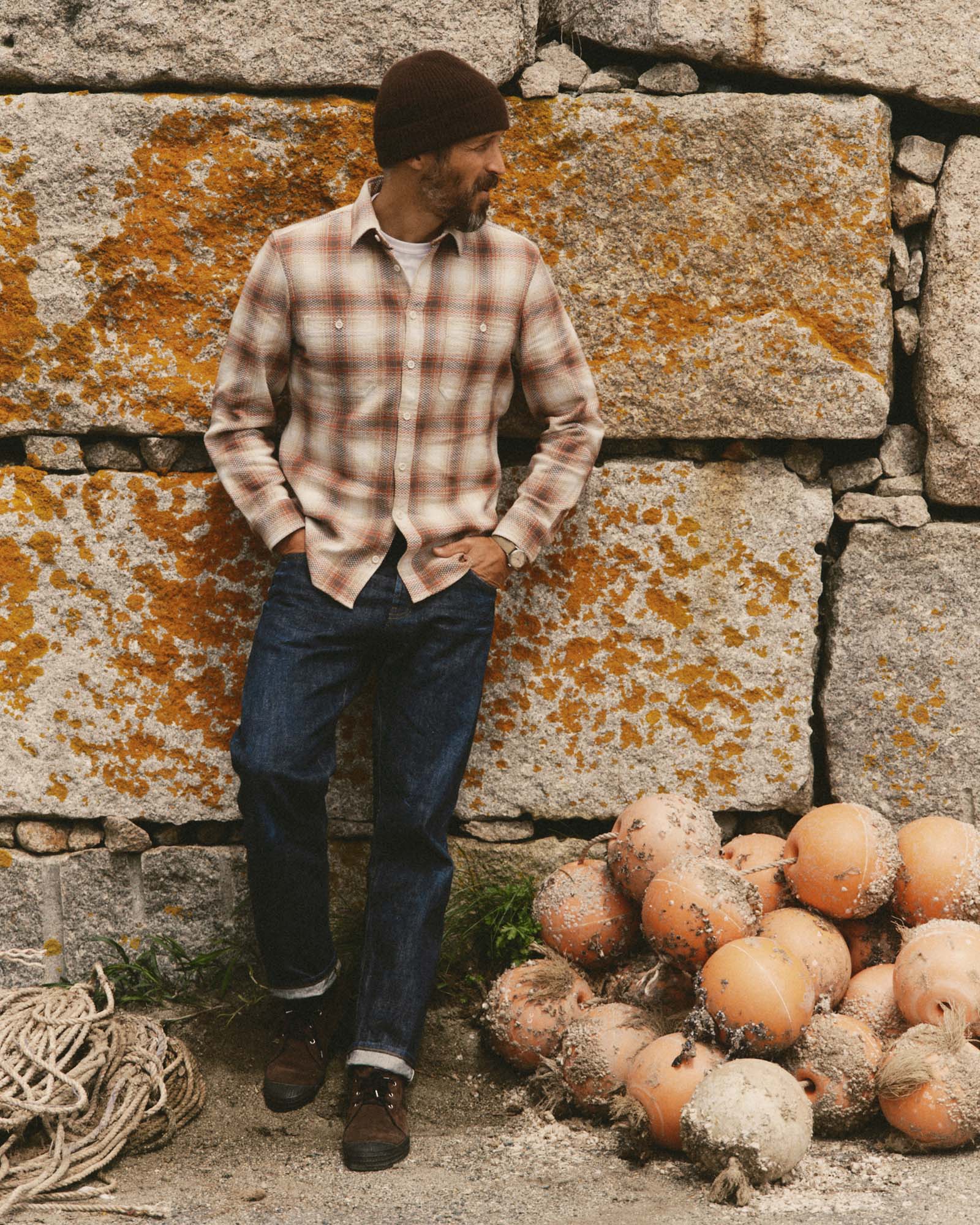 fit model leaning against the wall wearing The Straight Jean in Rinsed Organic Selvedge, Bottoms by Taylor Stitch