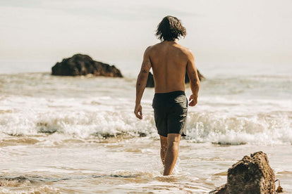 Our guy modeling the Adventure Short in Coal, strolling down a windy beach.