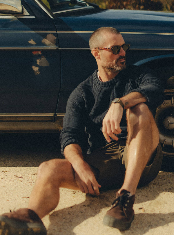 Model sitting on the ground by a vintage car