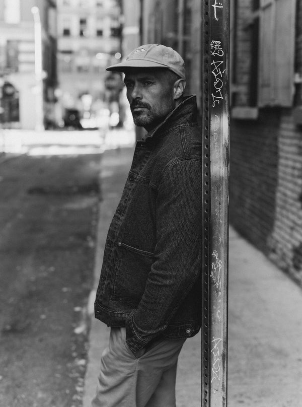 Black and white image of model leaning against a sign post