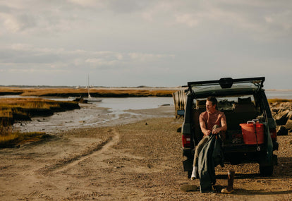 Model putting on an oyster-harvesting outfit at the back of his jeep