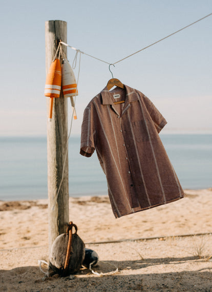 The Short Sleeve Hawthorne in Dried Fig Stripe, hanging on a clothesline by the beach
