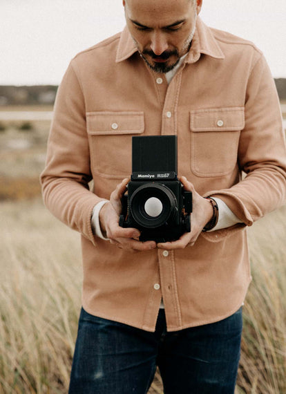 Model taking a photo in The Ledge Shirt in Dusty Coral Twill