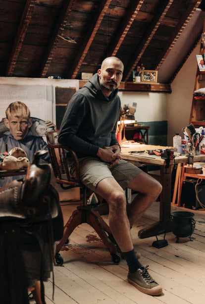 Model sitting in art studio, wearing The Cotton Hemp Hoodie in Asphalt