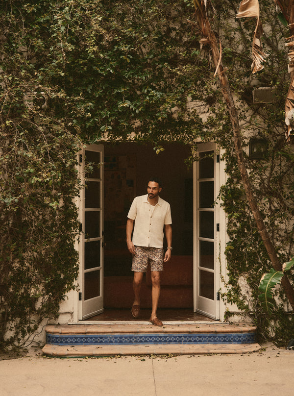 Model walking out of the doorway of an ivy covered house