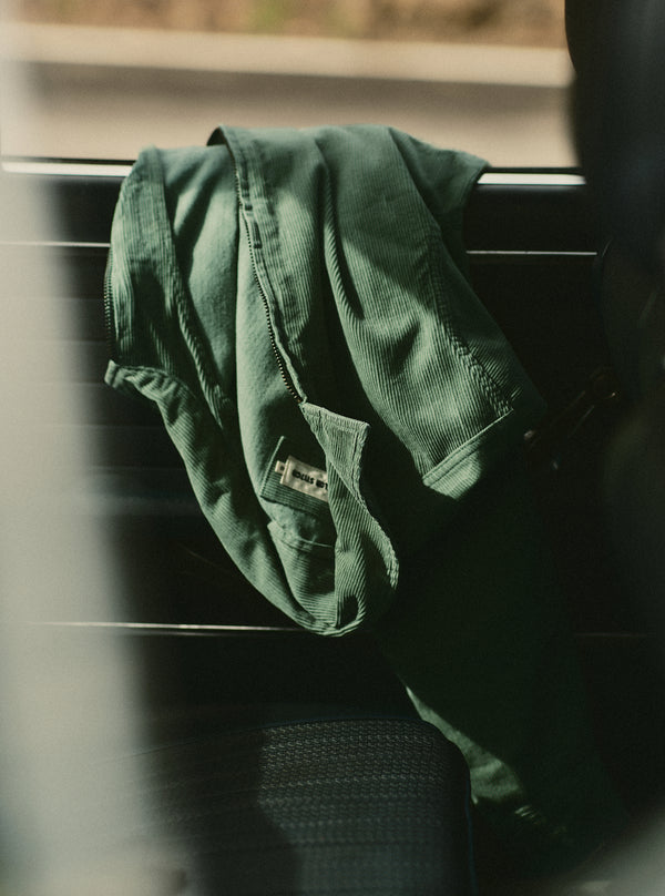 The Piston Jacket in Ivy Corduroy, draped over a car window