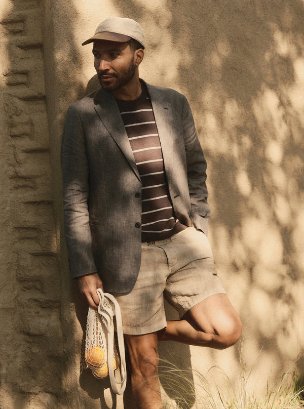 Model leaning against a wall, wearing The Stevens Sportcoat with a sweater tee and shorts