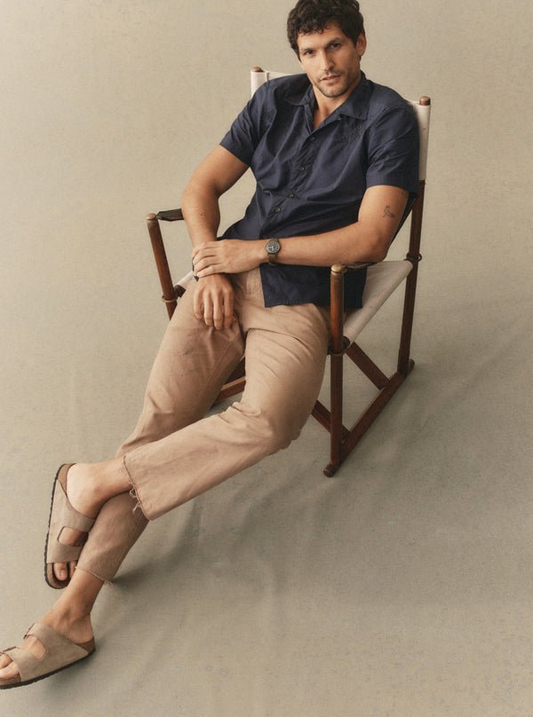 Model sitting on a chair, wearing The Davis Shirt in Navy Floral Embroidery