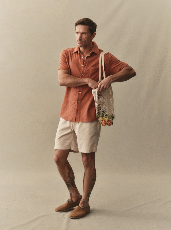 Model wearing the Short Sleeve California in Heather Driftwood, holding a tote of fruit