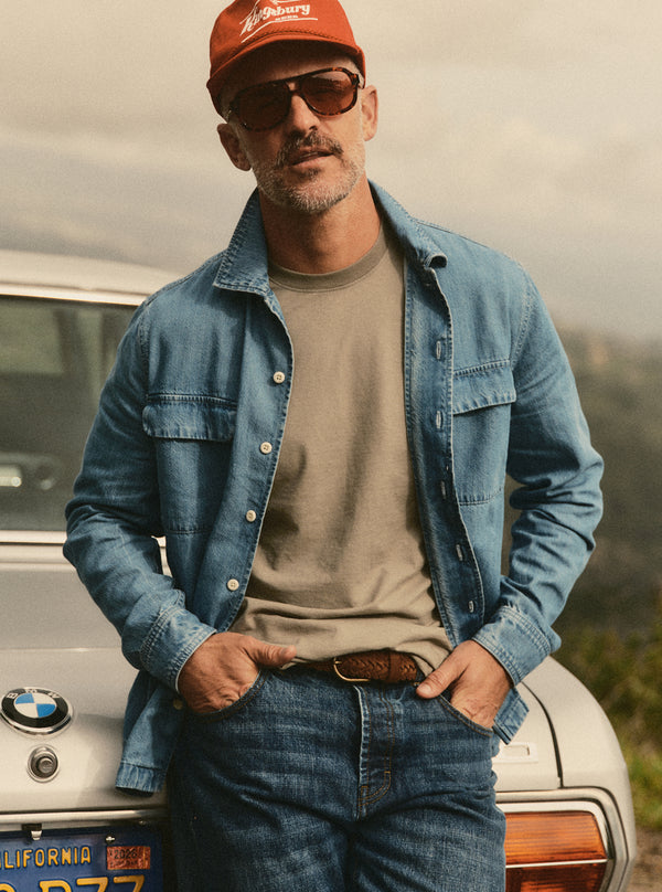 Model leaning against the boot of a car, wearing the Shore Shirt in Washed Indigo Twill