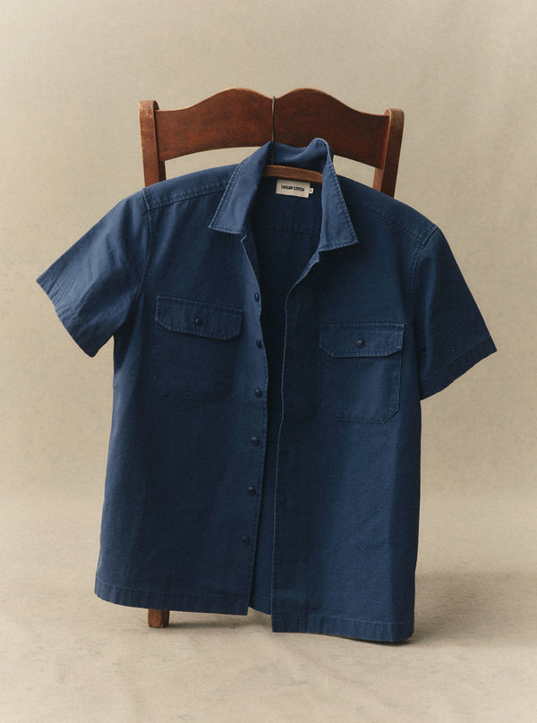 The Short Sleeve Mechanic Shirt hanging on the back of a wooden chair