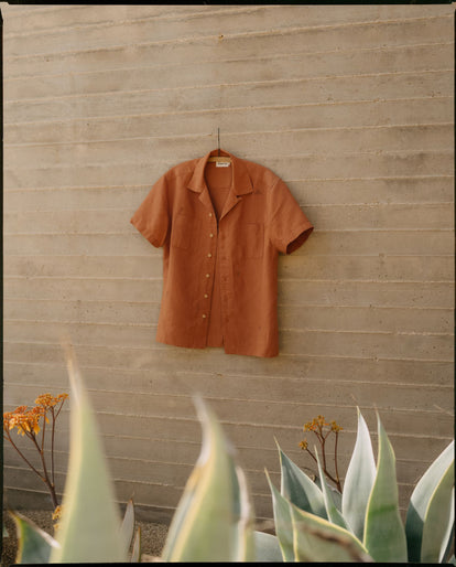 The Conrad Shirt in Adobe Embroidery, hanging on a wall outdoors