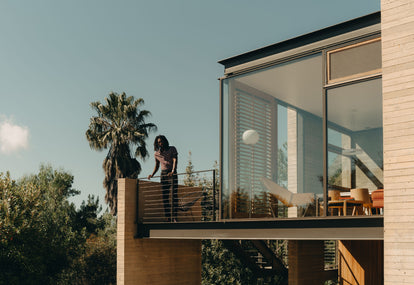 Model standing on the balcony of a mid-century modern home