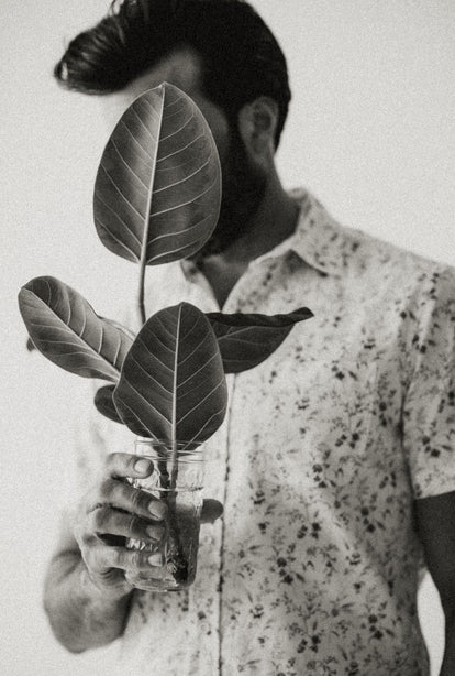 Model wearing The Short Sleeve California in Vintage Botanical, hiding his face behind a plant