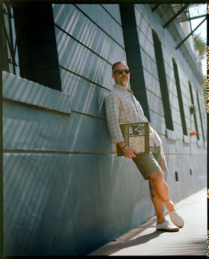 Model leaning against a wall in The Jack in Heather Flax Plaid