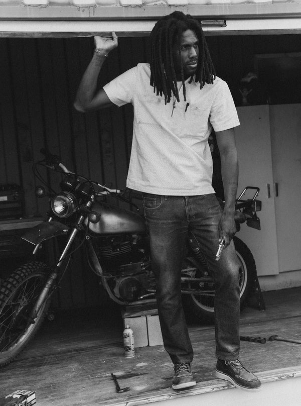 Model in a garage, wearing The Exhaust Shirt and denim jeans