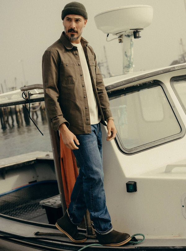Model walking next to a boat, wearing The Field Overshirt in Mushroom Ripstop