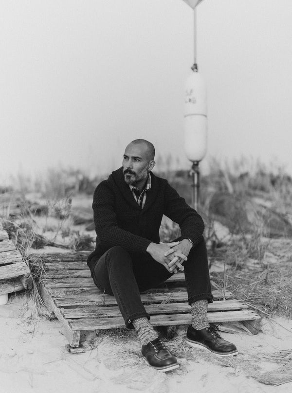 Model sitting on the beach in the Fisherman Shawl Cardigan