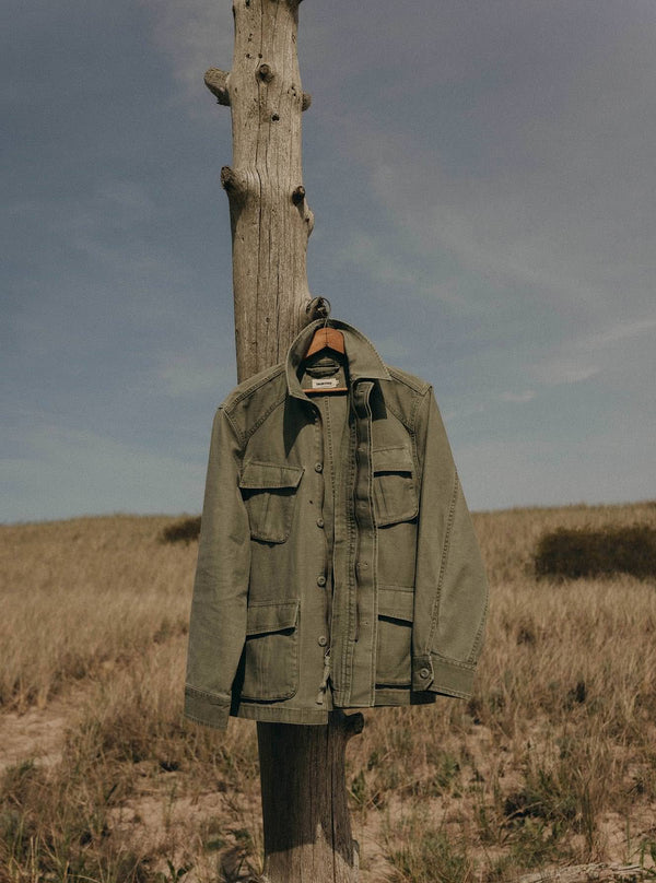 The Surplus Jacket hanging on a wooden post