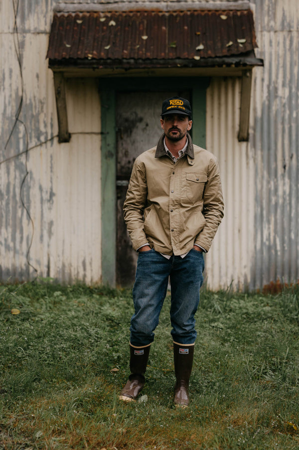 Model wearing The Deck Jacket in Khaki Dry Wax with jeans and boots