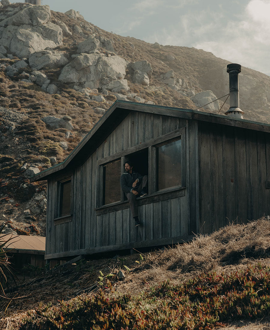 Model sitting on the window ledge of a cabin, by Taylor Stitch