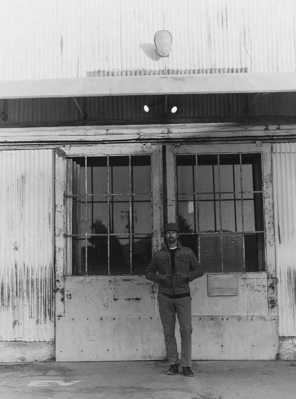 Model wearing The Roper Jacket in front of a warehouse