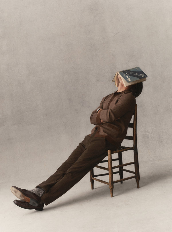 Model sitting on a chair with a book covering his face