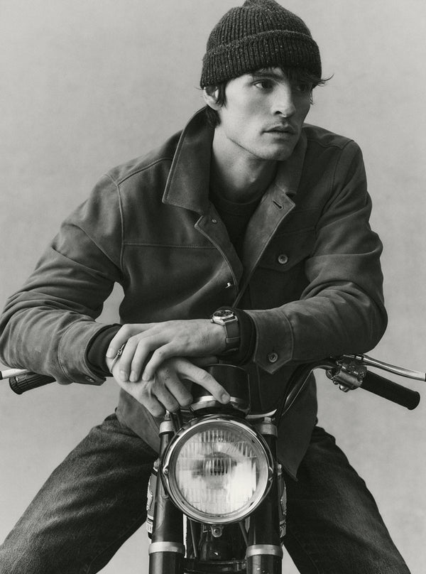 Model on a motorbike, wearing The Drover Jacket