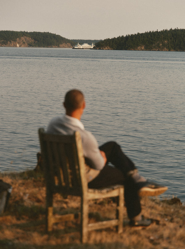 Model sitting on a chair, looking out at the coast