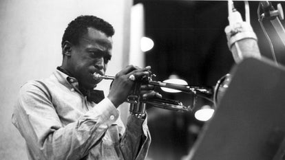 Miles Davis playing the trumpet, wearing an oxford shirt