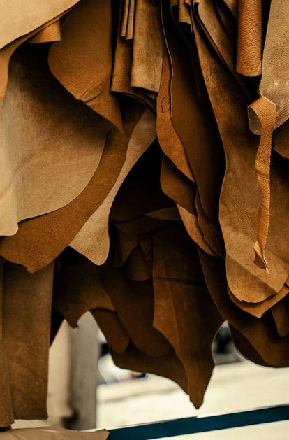 Many cuts of leather in various textures and shades of brown are suspended in the air.