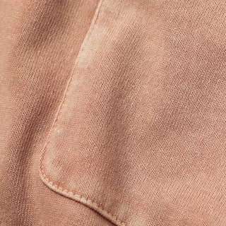 Closeup image of the pocket of a pale pink knit tee shirt.