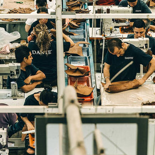 A group of men and women in black t-shirts work in a factory—sewing, cutting, etc.