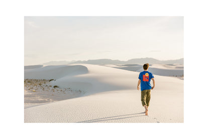 A film photo of a man walking through desert dunes