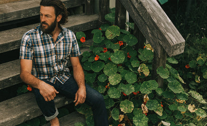 Our guy sitting on his stoop in a shot-sleeved madras fabric shirt.