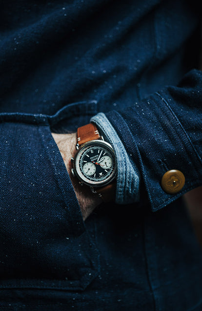 Close-up shot of a TS x Jack Mason watch on our guy's wrist, hand in pocket of a blue Ojai Jacket with a utility shirt cuff just showing.