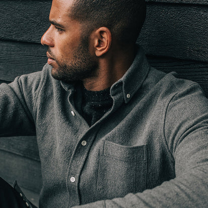 Our guy sitting with his back to a black varnished wooden wall.