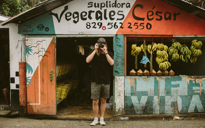 A photo of someone taking a photo right back, standing in the doorway of a roadside fruit shack.