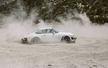 A white Porsche, kicking up dust.