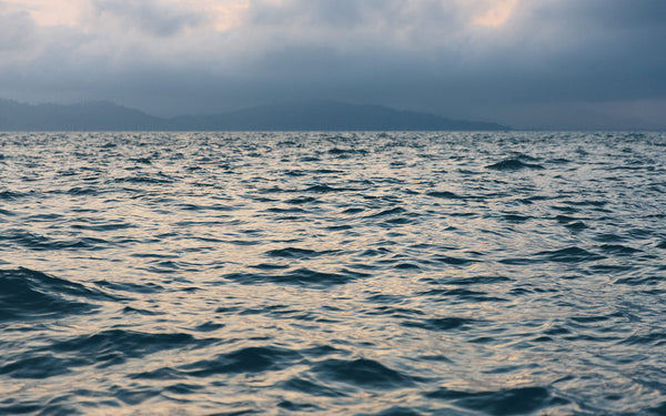 Rippling waves on the ocean with mountains in the background.