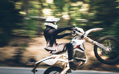 A motocross rider pulling a wheelie.