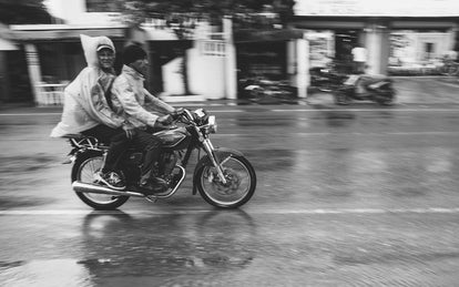 Two guys on a motorcycle, in the rain.
