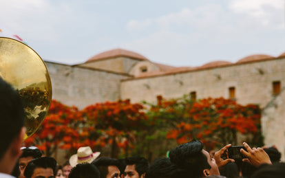 Cropped shot of a red-tiled roof, with a mariachi band and socializing party-goers.