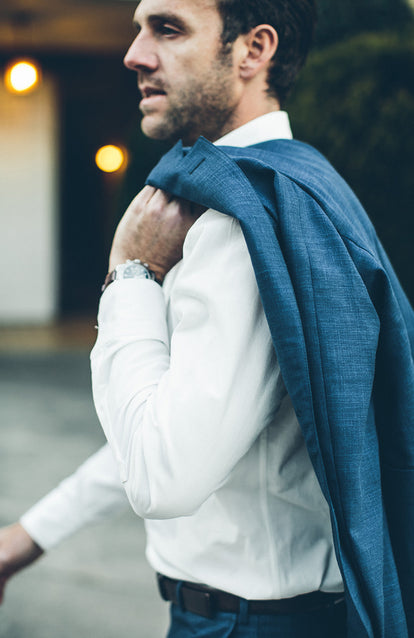 Our guy walking with his blue suit jacket slung over his shoulder.