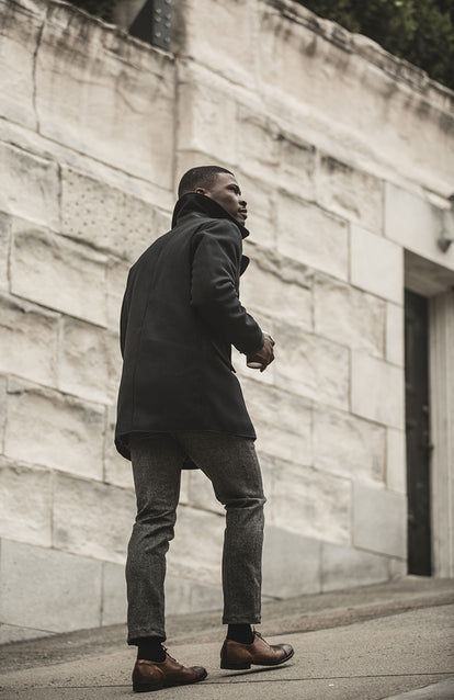 Our guy walking up a steep sidewalk, wearing a peacoat and oxford shoes.