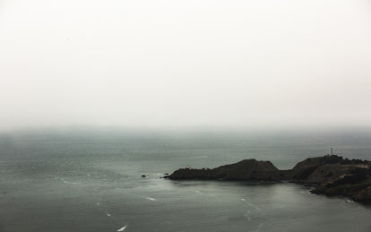A misty ocean scene with a rocky promontory.