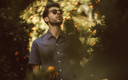 Our guy picking oranges in a floral short sleeved shirt.
