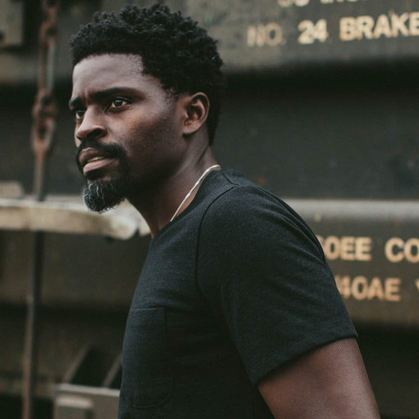 Our guy in a black tee, shot against a shipping container.